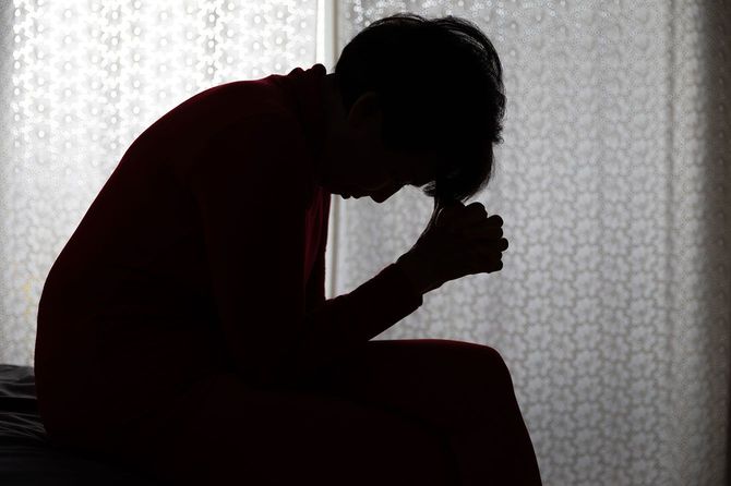 座ってうつむく人のシルエット