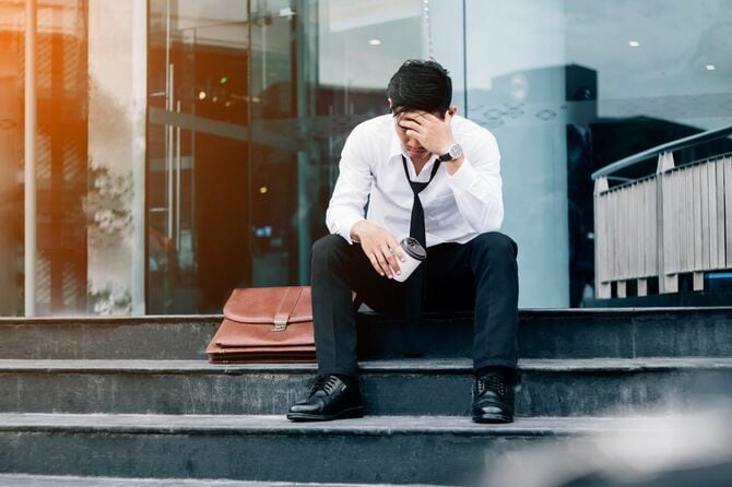 屋外の階段に座り込み、思い悩んでいる男性