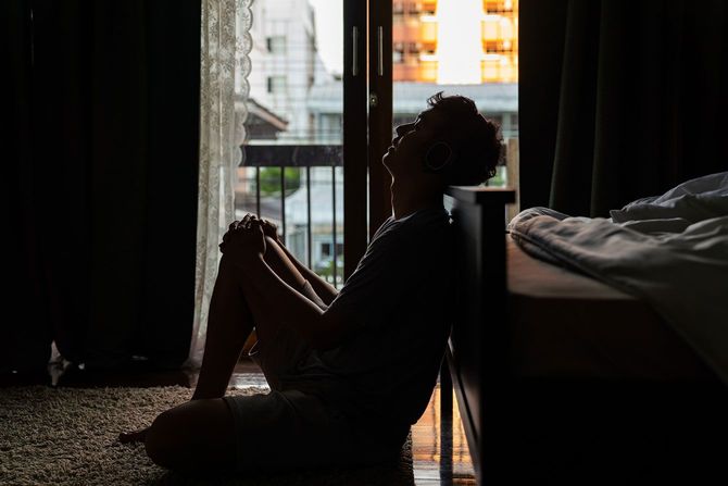一人で薄暗い部屋の床に座っている男性