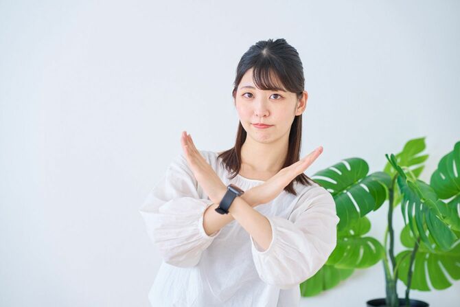 身体の前で手を使ってバツ印を作る女性
