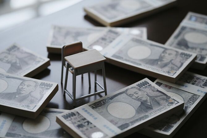 1万円札の束とミニチュアの机と椅子