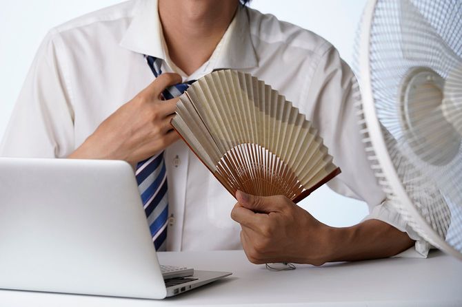 オフィスで暑そうにしているビジネスパーソン
