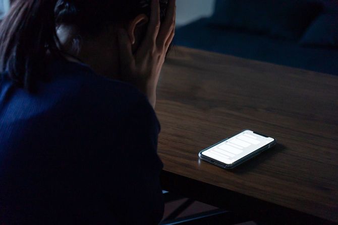 電話の前でショックを受ける女性