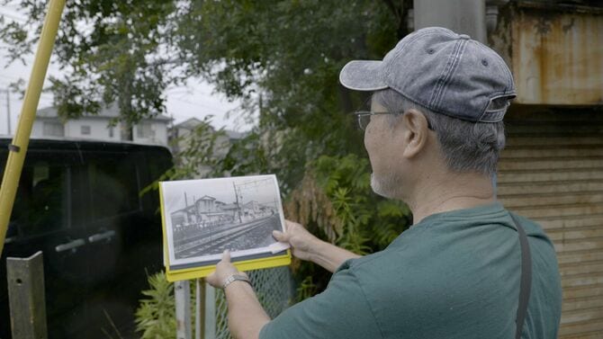 当時の現場検証写真を示しながら説明する山崎さん。JR東海道線の線路とその奥にあったのが味噌工場。