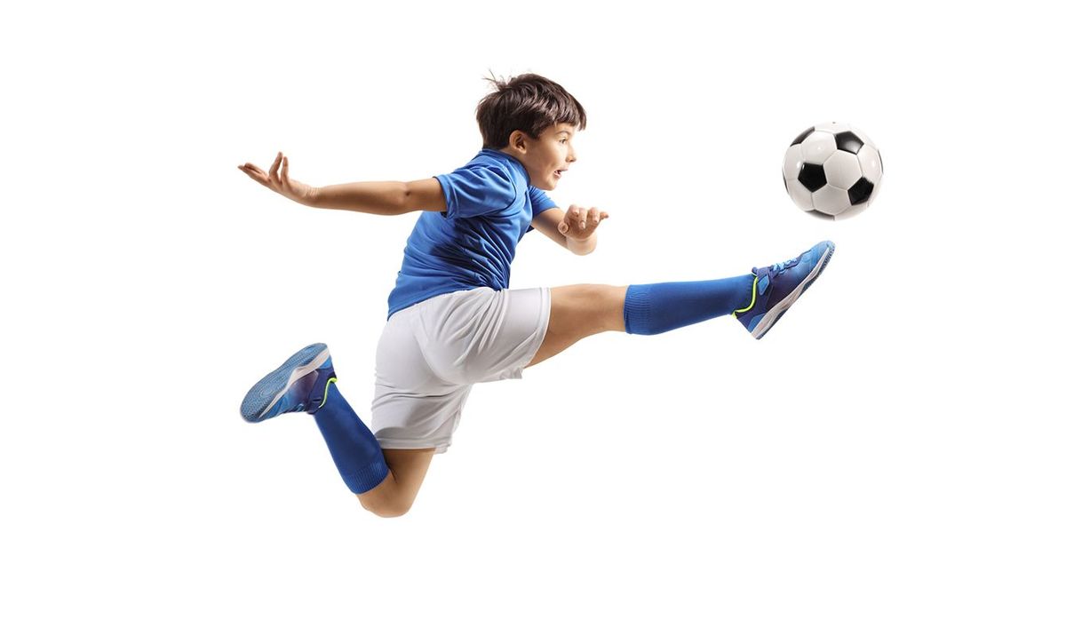 スポーツジャージを着てサッカーボールを蹴る少年