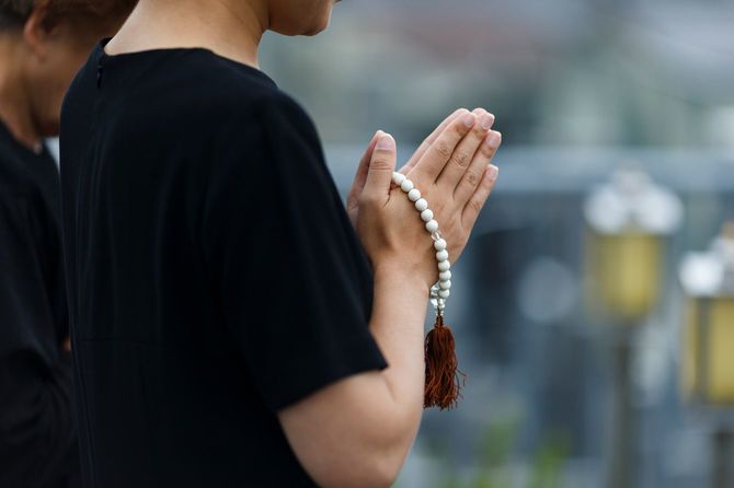 喪服で手を合わせる女性