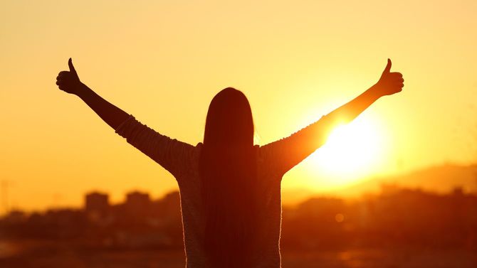 夕陽に向かってサムズアップする女性のシルエット