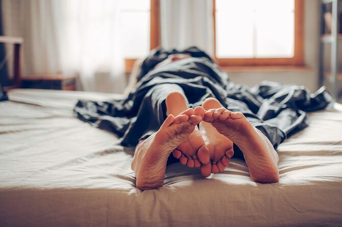 ベッドで寝ているカップルの足