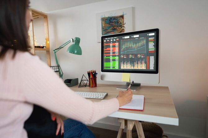 自宅のパソコンで株取引きの画面を確認する女性