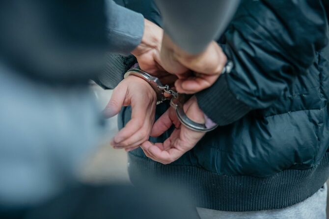 警官が犯罪者の背中の手錠をもつ