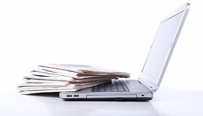 ラップトップの隣にある新聞