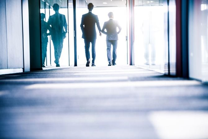 日当たりの良い廊下を歩いていく二人の男性社員