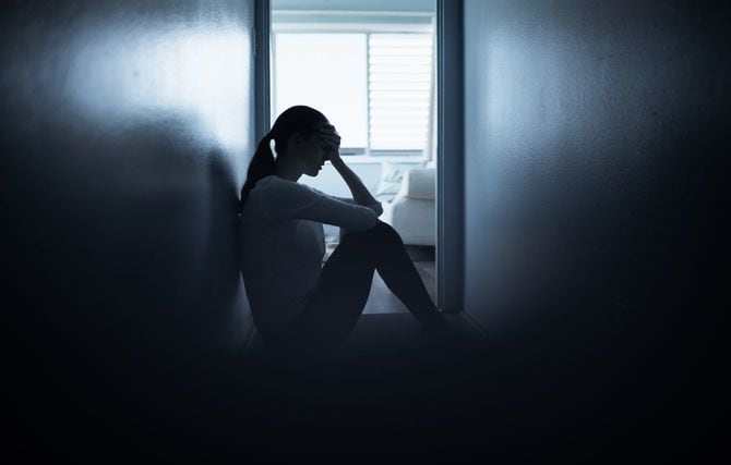 家の床に座っている悲しい女性