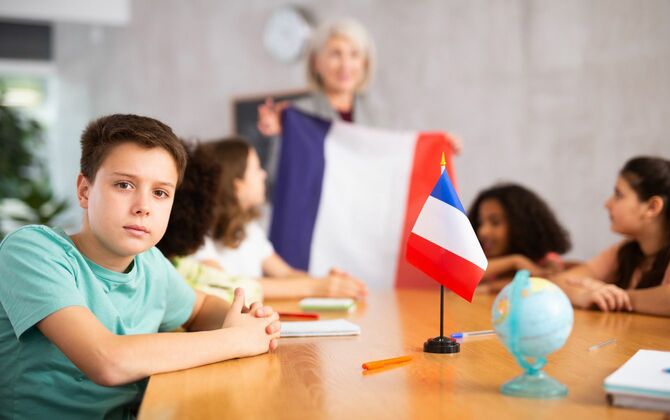地理の授業で子供たちにフランスの国旗を見せる女性教師