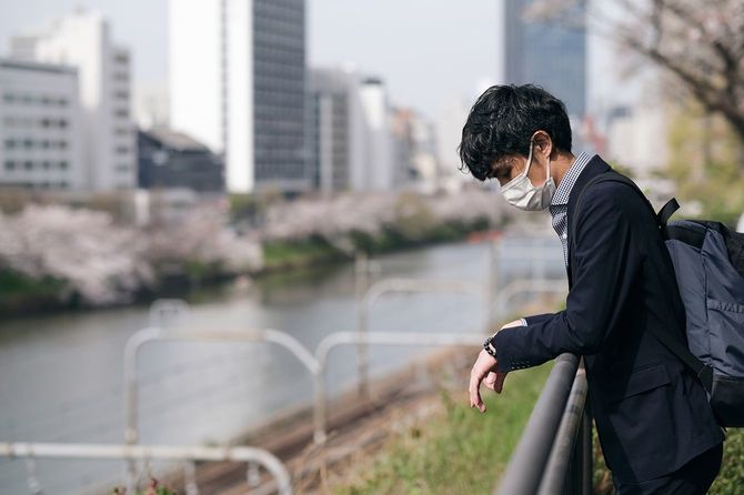 外でマスクをしてうなだれる人のイメージ