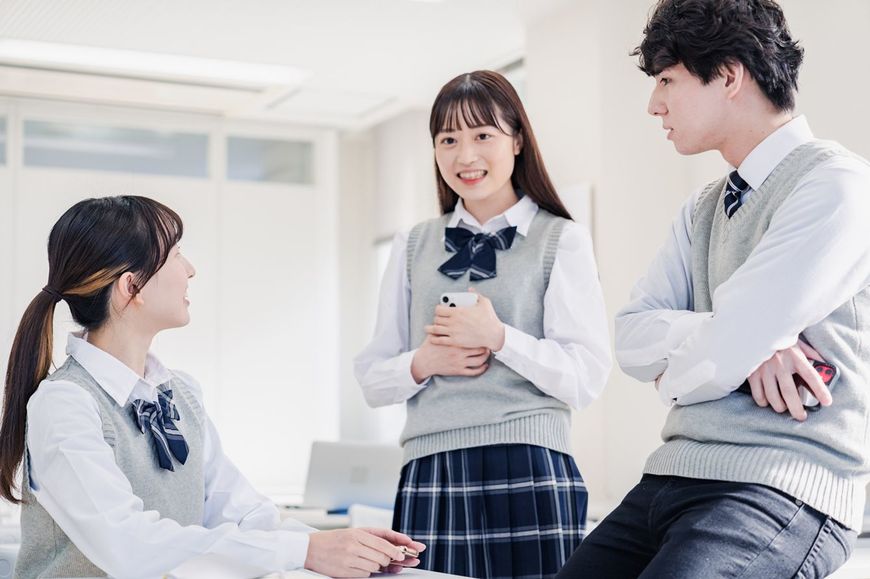 教室でクラスメートとおしゃべりをする高校生