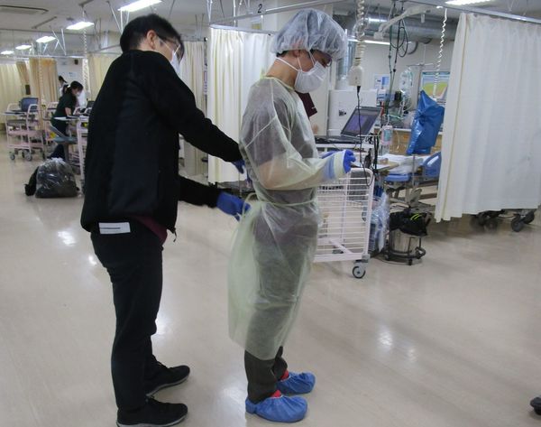これからコロナ入院患者に接するERの医師に防護服を装着する