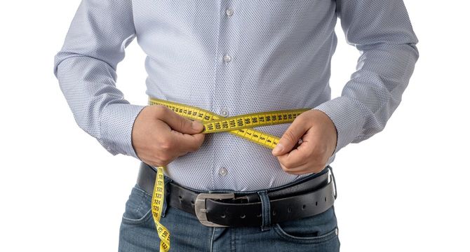 お腹周りを巻き尺で測っている男性