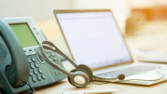 コールセンターのデスクに電話、インカム、ノートパソコン