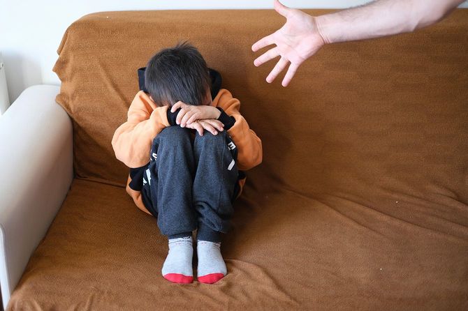 膝を抱えて座っている子ども