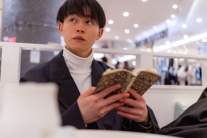 カフェで本を読む若い男性