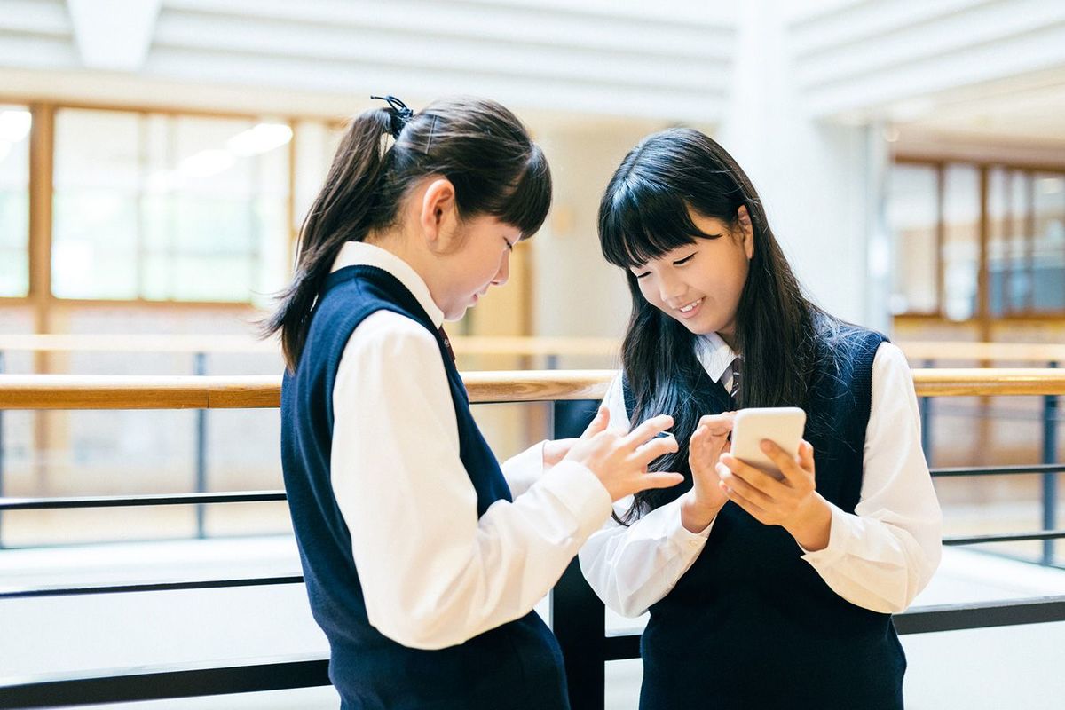 学校で友達とスマホを見ている女子生徒