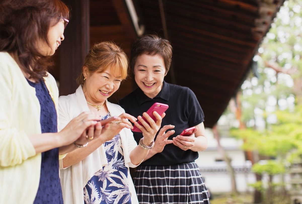 スマートフォンで一緒に写真を見る3人のシニア女性