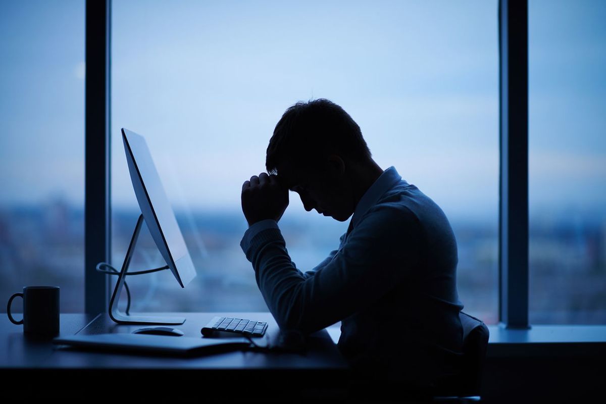 オフィスでコンピュータの前に座っているストレスの多いビジネスマン