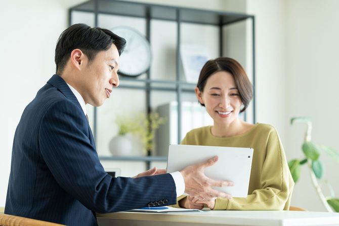 相手に書類を見せながら説明をするビジネスマン