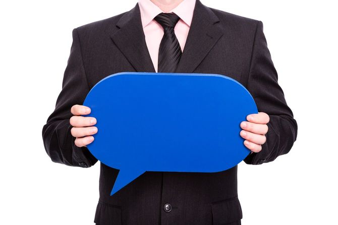 青い吹き出し型の板を持つスーツの男性