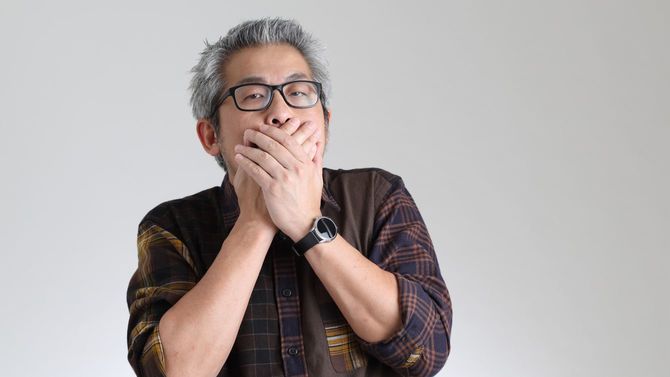 口を手で押さえ、言葉をグッと飲み込む男性