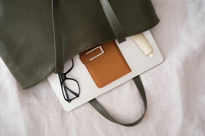 ダークグリーンのバッグに入ったノート、メガネ、財布、ハンドクリーム