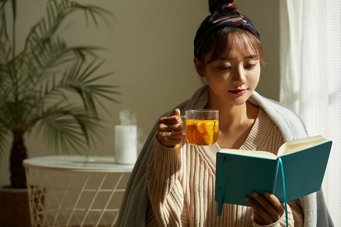 フルーツティーを飲みながら家でリラックスしている若いアジアの女性