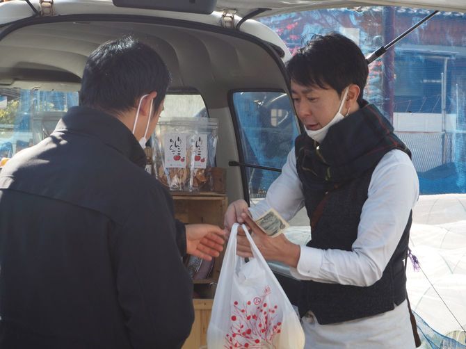 袋に入った商品と代金をやり取りする片山さん