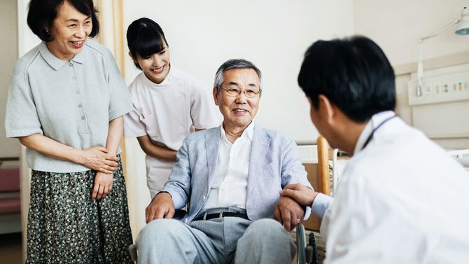 シニアの患者とその家族に話しかける医師と看護婦