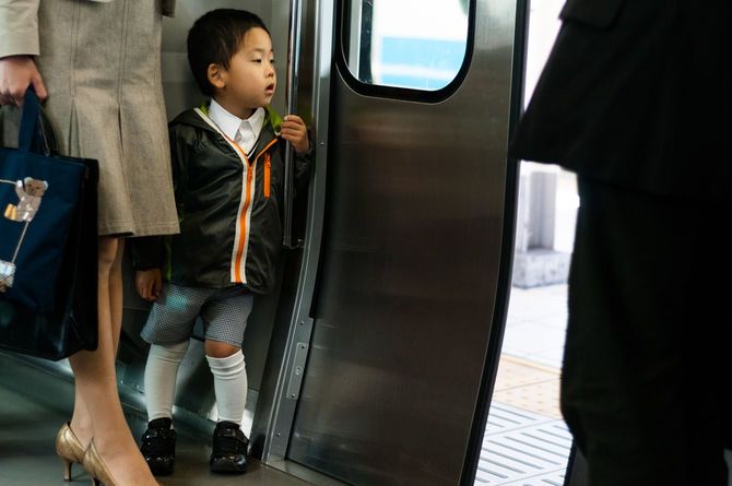 電車のドアから外を眺めている日本の子ども