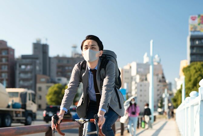 マスク着用で自転車通勤する男性