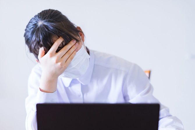 PCの前で悩んでいる、マスクを着用した人