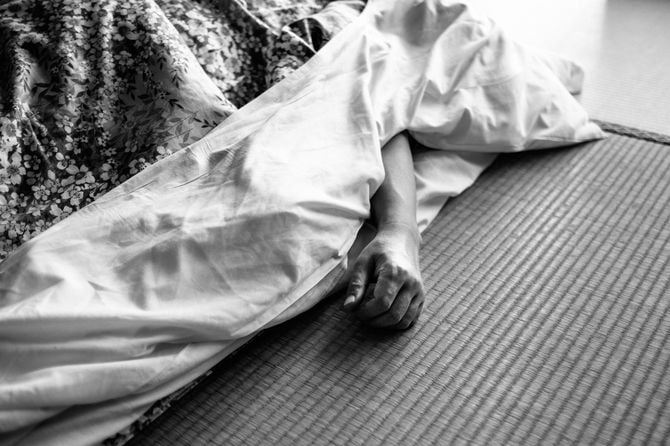 寝具から突き出た男の手