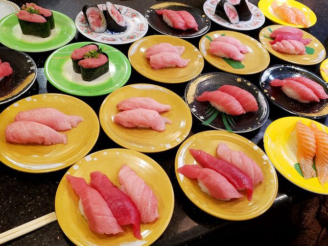 テーブルいっぱいに並んだマグロ中心の回転寿司の皿