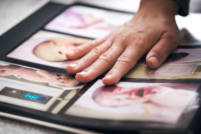 アルバムに写真を貼り付ける女性の手元