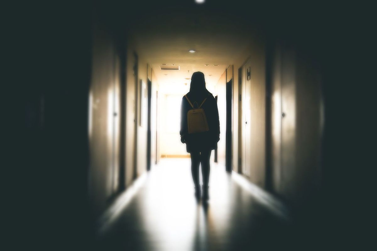 暗い建物の通路を歩く若い女性