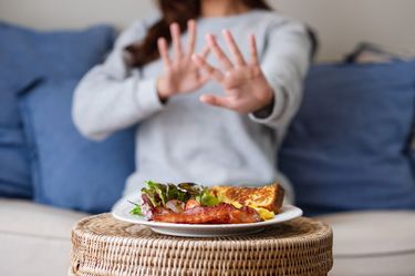 ダイエットのためにテーブルの上の食べ物を拒否する女性