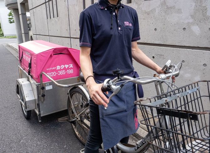 「なんでも酒やカクヤス」と書かれたピンクの荷車のついた電動自転車