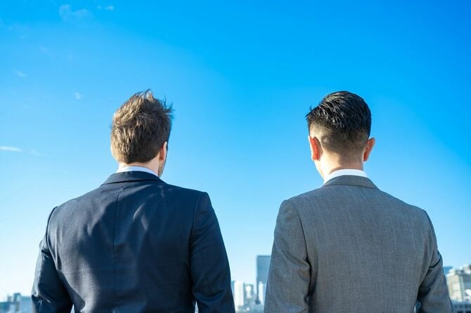 よく晴れた日の屋上から街を見下ろす二人のビジネスパーソン