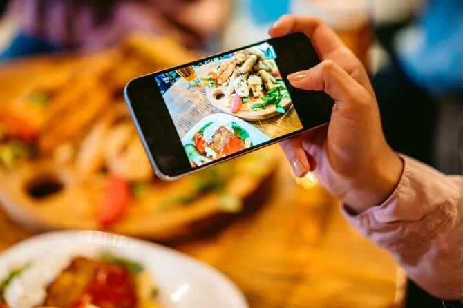 レストランで運ばれてきた食事をスマートフォンで撮影する人