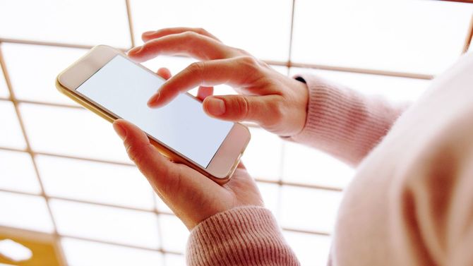 障子のそばでスマホを操作する女性の手元