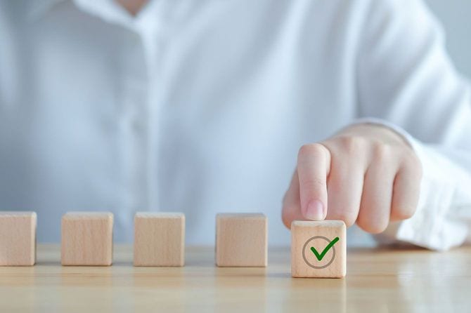 チェックマークのついた木製のブロックを指さす人