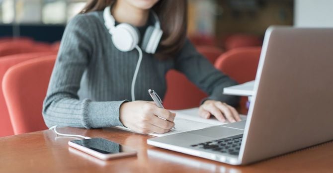 ラップトップを開いて勉強する女性