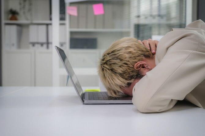 オフィスでノートパソコンに突っ伏している人